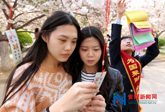 安阳工学院樱花园,两名女大学生正在仔细品味樱花书签内容:纳税没有